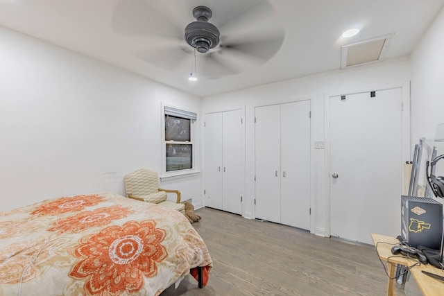 bedroom featuring ceiling fan, light wood-type flooring, and multiple closets