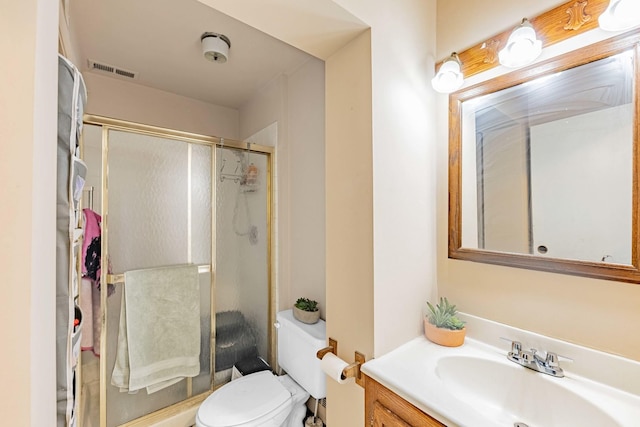 bathroom featuring vanity, toilet, and a shower with shower door