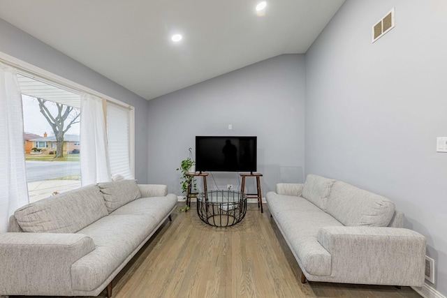 living room featuring wood-type flooring and vaulted ceiling