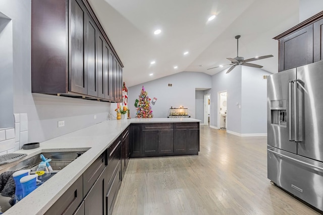 kitchen with kitchen peninsula, high end refrigerator, dark brown cabinets, and vaulted ceiling