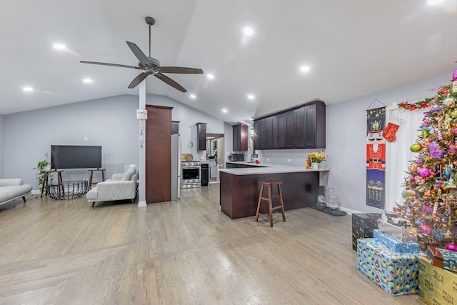 kitchen featuring kitchen peninsula, a kitchen bar, stainless steel appliances, ceiling fan, and lofted ceiling