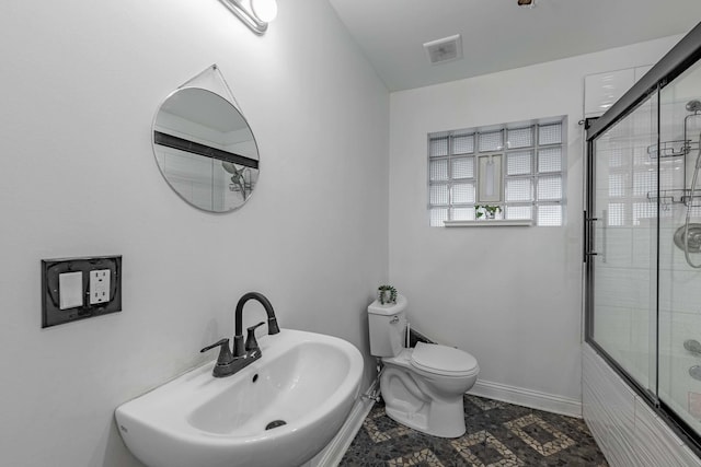 full bathroom featuring shower / bath combination with glass door, sink, and toilet