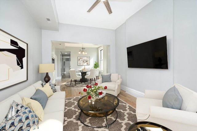 living room featuring wood-type flooring and ceiling fan with notable chandelier