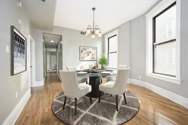 dining space featuring wood-type flooring and a notable chandelier