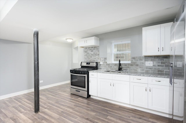 kitchen with white cabinets, stainless steel range with gas cooktop, light stone countertops, and sink