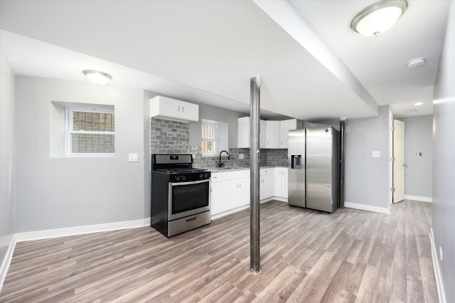 kitchen featuring appliances with stainless steel finishes, tasteful backsplash, sink, light hardwood / wood-style flooring, and white cabinets