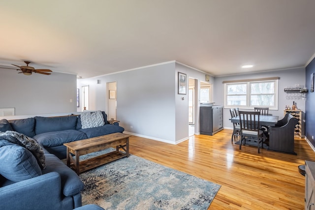 living room featuring crown molding, light hardwood / wood-style flooring, and ceiling fan