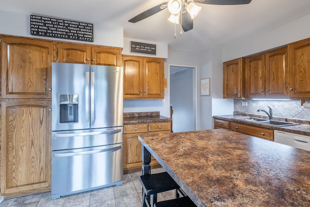 kitchen with backsplash, sink, ceiling fan, a kitchen bar, and stainless steel fridge with ice dispenser