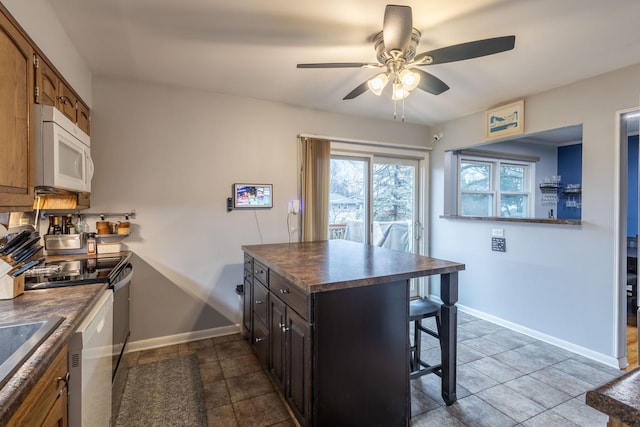 kitchen with a breakfast bar, ceiling fan, and stainless steel range with electric stovetop