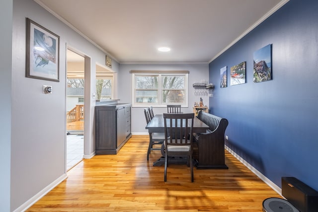 dining space with light wood-type flooring and ornamental molding