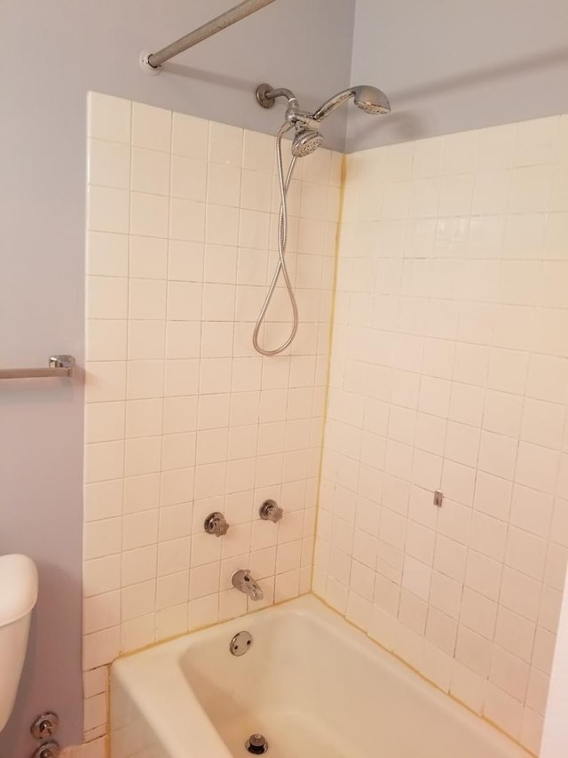 bathroom featuring tiled shower / bath combo and toilet