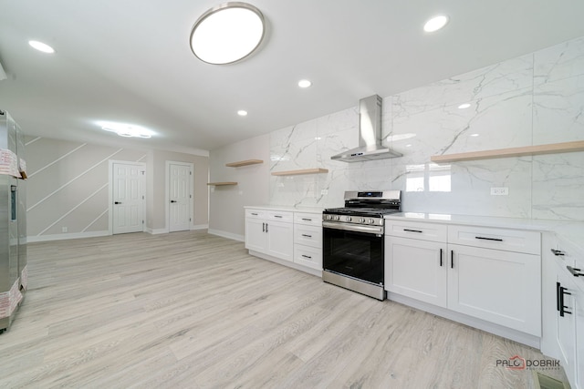 kitchen with white cabinetry, stainless steel stove, wall chimney range hood, and light wood-type flooring