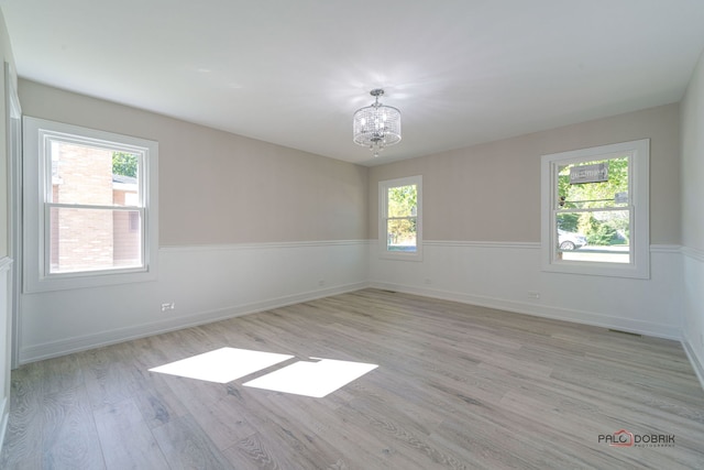 unfurnished room featuring light hardwood / wood-style flooring, a wealth of natural light, and a chandelier