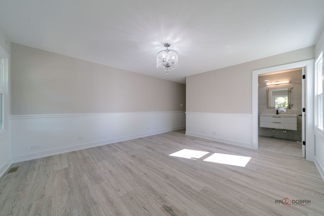 unfurnished room featuring light hardwood / wood-style flooring and a notable chandelier