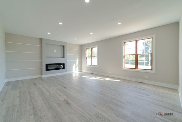 unfurnished living room featuring built in features and light hardwood / wood-style floors