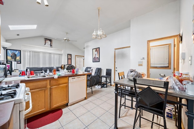 kitchen featuring pendant lighting, white appliances, vaulted ceiling with skylight, light tile patterned floors, and ceiling fan with notable chandelier