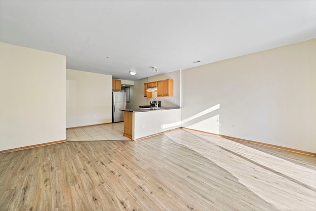 unfurnished living room with sink and light hardwood / wood-style flooring