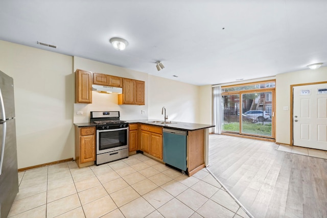 kitchen with kitchen peninsula, appliances with stainless steel finishes, light tile patterned floors, and sink