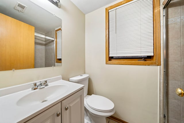 bathroom with vanity, toilet, and a shower with door