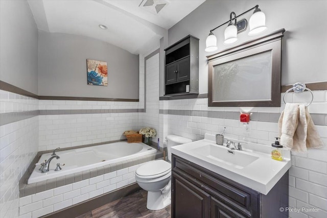 bathroom featuring tiled tub, vanity, hardwood / wood-style flooring, and toilet