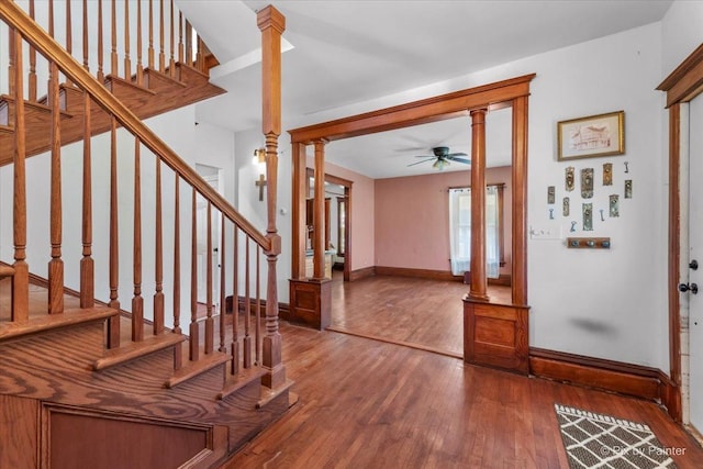 foyer featuring ornate columns, wood-type flooring, and ceiling fan