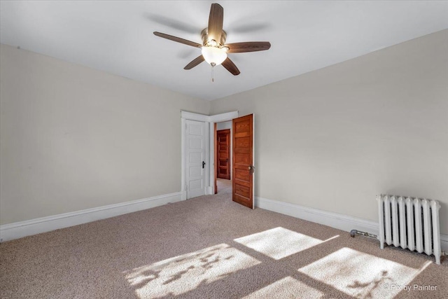 carpeted empty room with ceiling fan and radiator