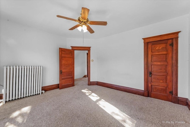 carpeted empty room with ceiling fan and radiator