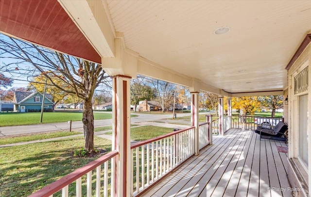 wooden terrace featuring a porch and a yard