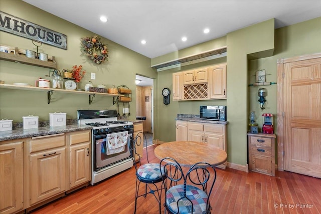 kitchen with hardwood / wood-style floors, stainless steel gas range oven, and light brown cabinets