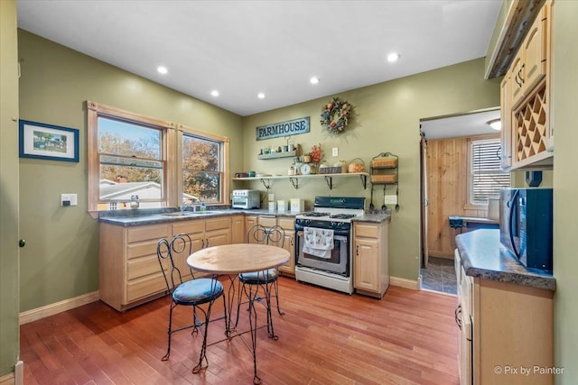 kitchen featuring sink, gas range, light wood-type flooring, and light brown cabinets