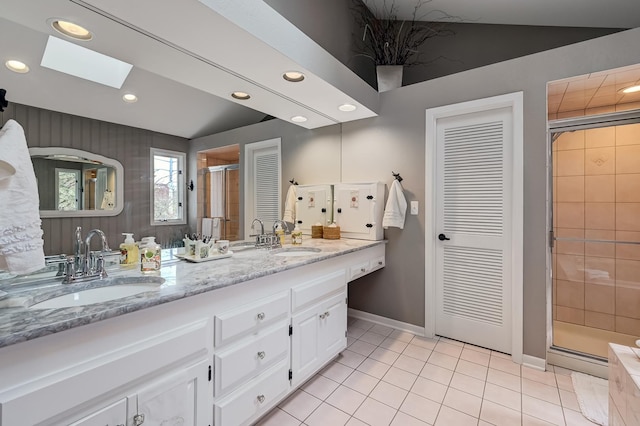 bathroom featuring tile patterned floors, vanity, vaulted ceiling with skylight, and a shower with shower door