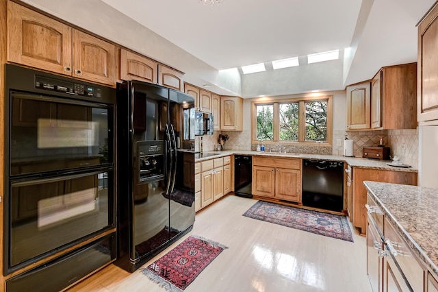 kitchen featuring sink, tasteful backsplash, light hardwood / wood-style flooring, lofted ceiling, and black appliances