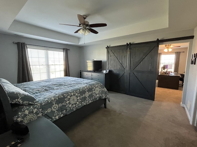 bedroom with carpet, a barn door, a raised ceiling, and ceiling fan