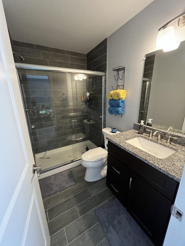 bathroom with walk in shower, tile patterned floors, vanity, and toilet