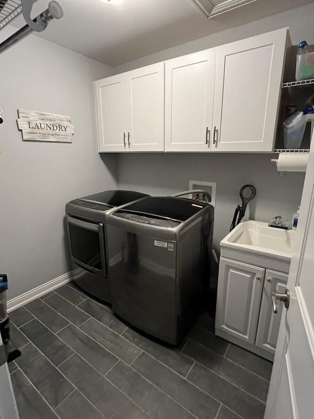 clothes washing area with separate washer and dryer, sink, dark tile patterned floors, and cabinets