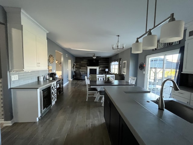 kitchen featuring pendant lighting, backsplash, dark wood-type flooring, white cabinets, and sink