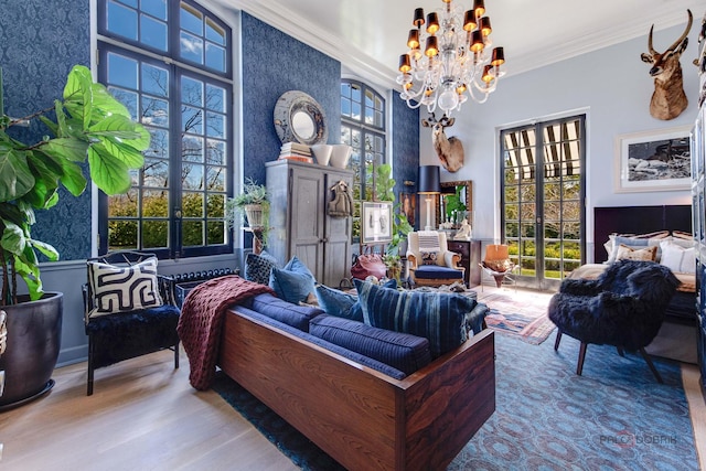 sitting room with ornamental molding, a wealth of natural light, a notable chandelier, and wood finished floors