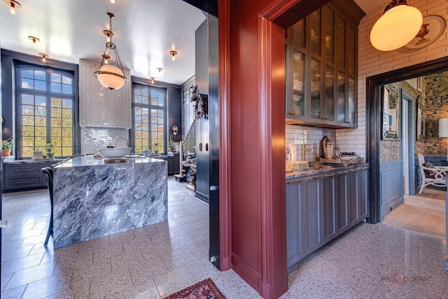 bar featuring light speckled floor, decorative light fixtures, and decorative backsplash