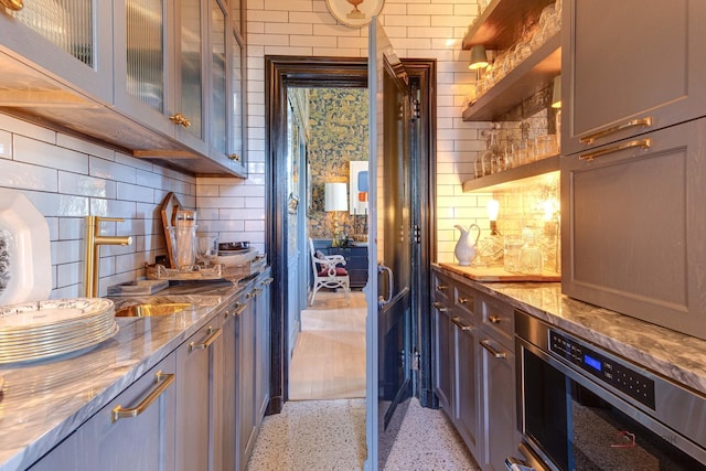 bar with light speckled floor, backsplash, and oven