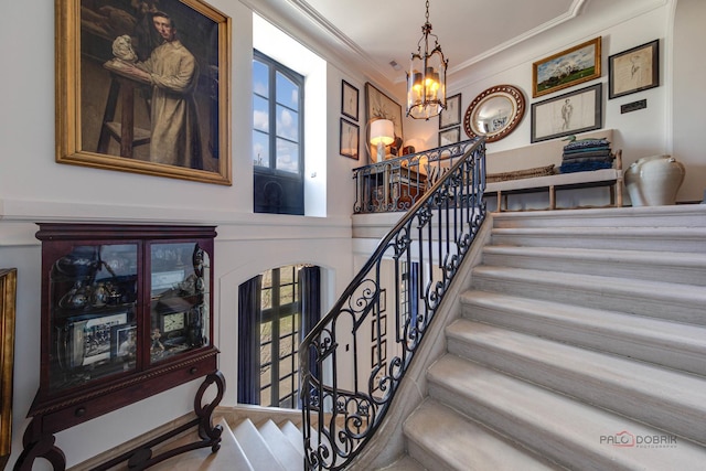 stairs with a chandelier and crown molding