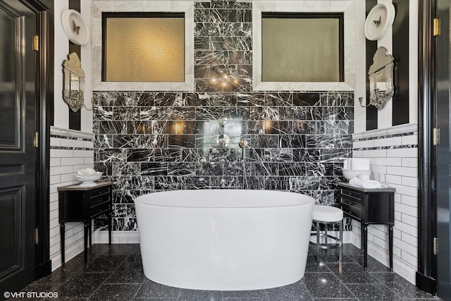 bathroom featuring a soaking tub, granite finish floor, and tile walls