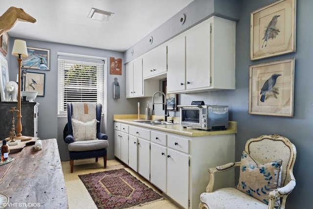 kitchen with light countertops, white cabinets, and a sink