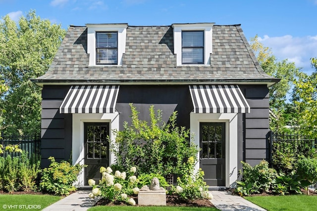 view of front of property featuring a shingled roof and fence