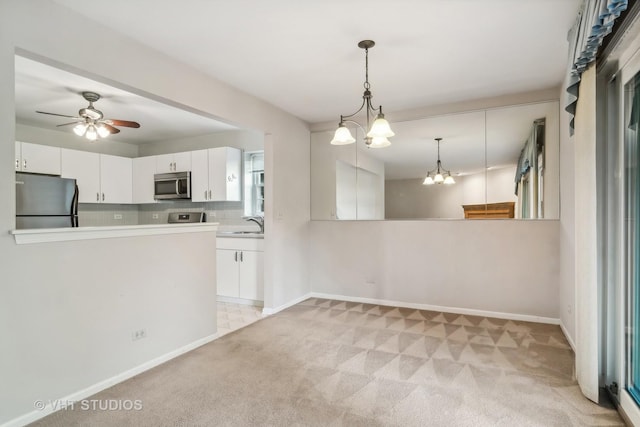 kitchen featuring stainless steel appliances, backsplash, pendant lighting, light colored carpet, and white cabinets