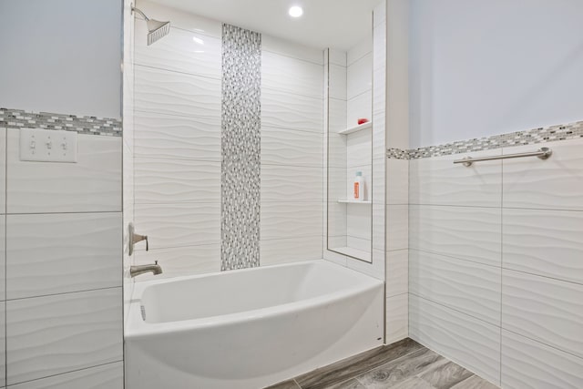 bathroom with tiled shower / bath combo and tile walls