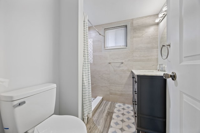 bathroom featuring tiled shower, vanity, and toilet