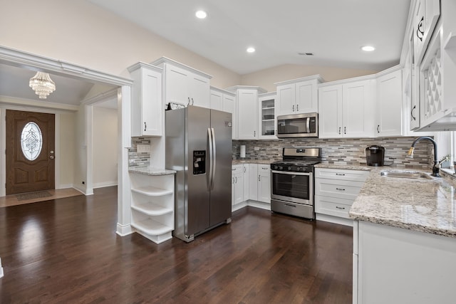 kitchen with light stone countertops, sink, lofted ceiling, white cabinets, and appliances with stainless steel finishes