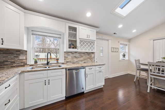 kitchen with white cabinetry, dishwasher, sink, light stone counters, and lofted ceiling with skylight