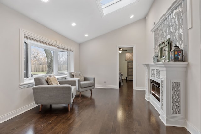 sitting room featuring vaulted ceiling with skylight, ceiling fan, and dark wood-type flooring