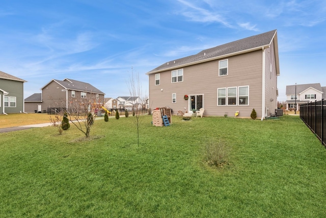 rear view of property featuring central air condition unit and a lawn